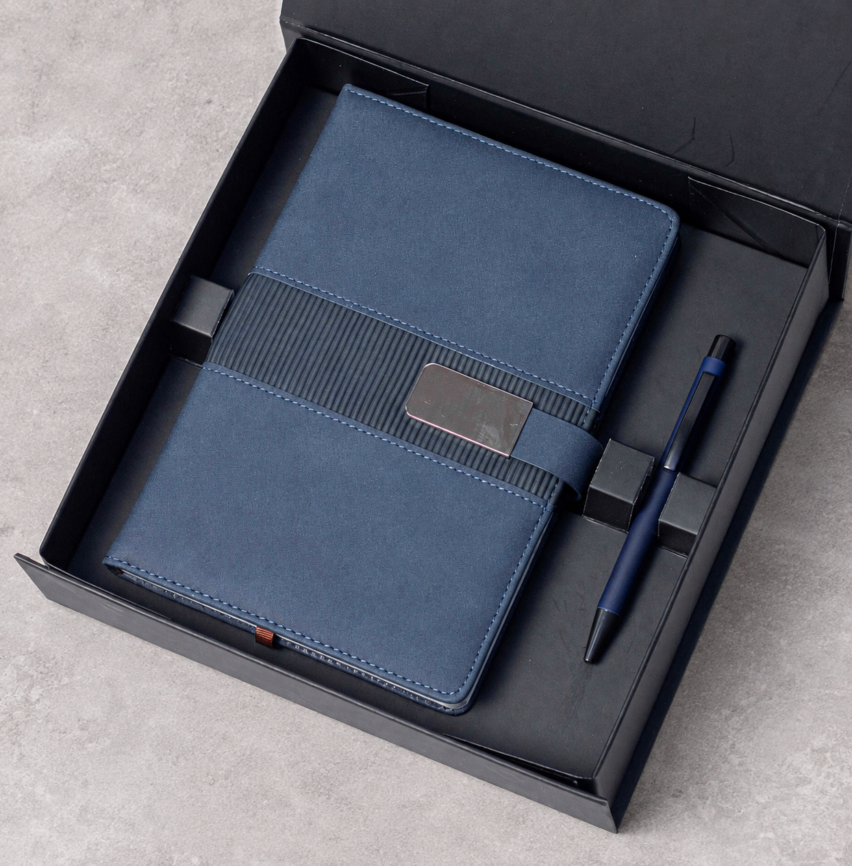 Notebook with buckle closure and matching pen arranged in a gift box