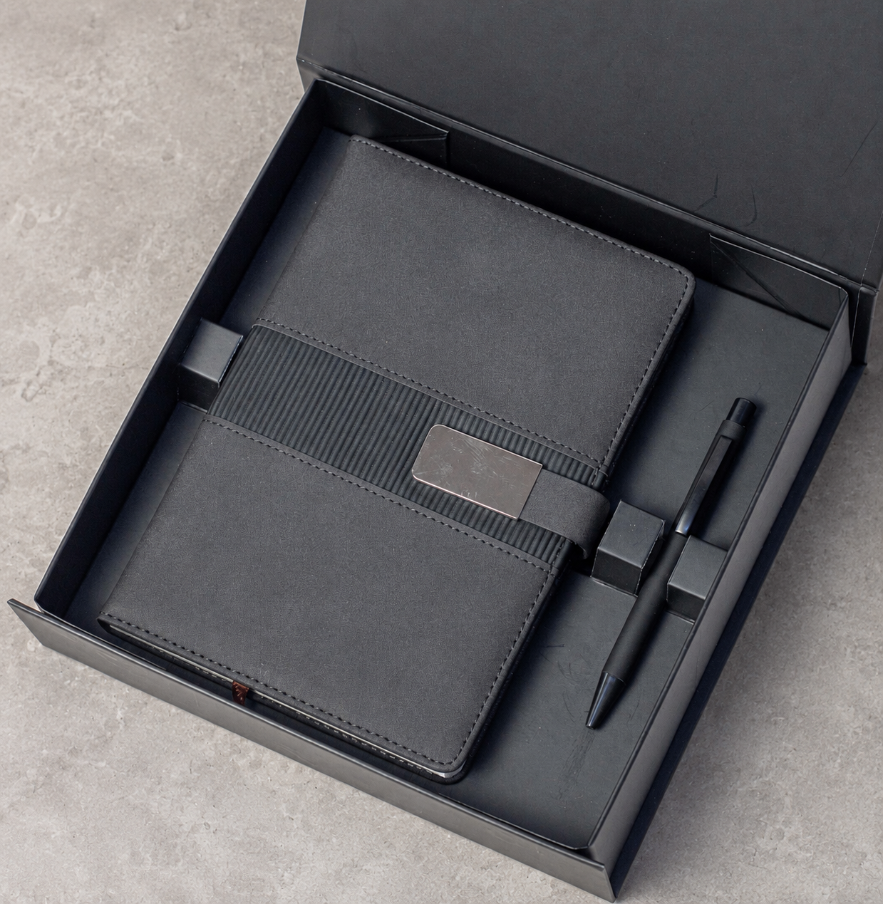 Notebook with buckle closure and matching pen arranged in a gift box