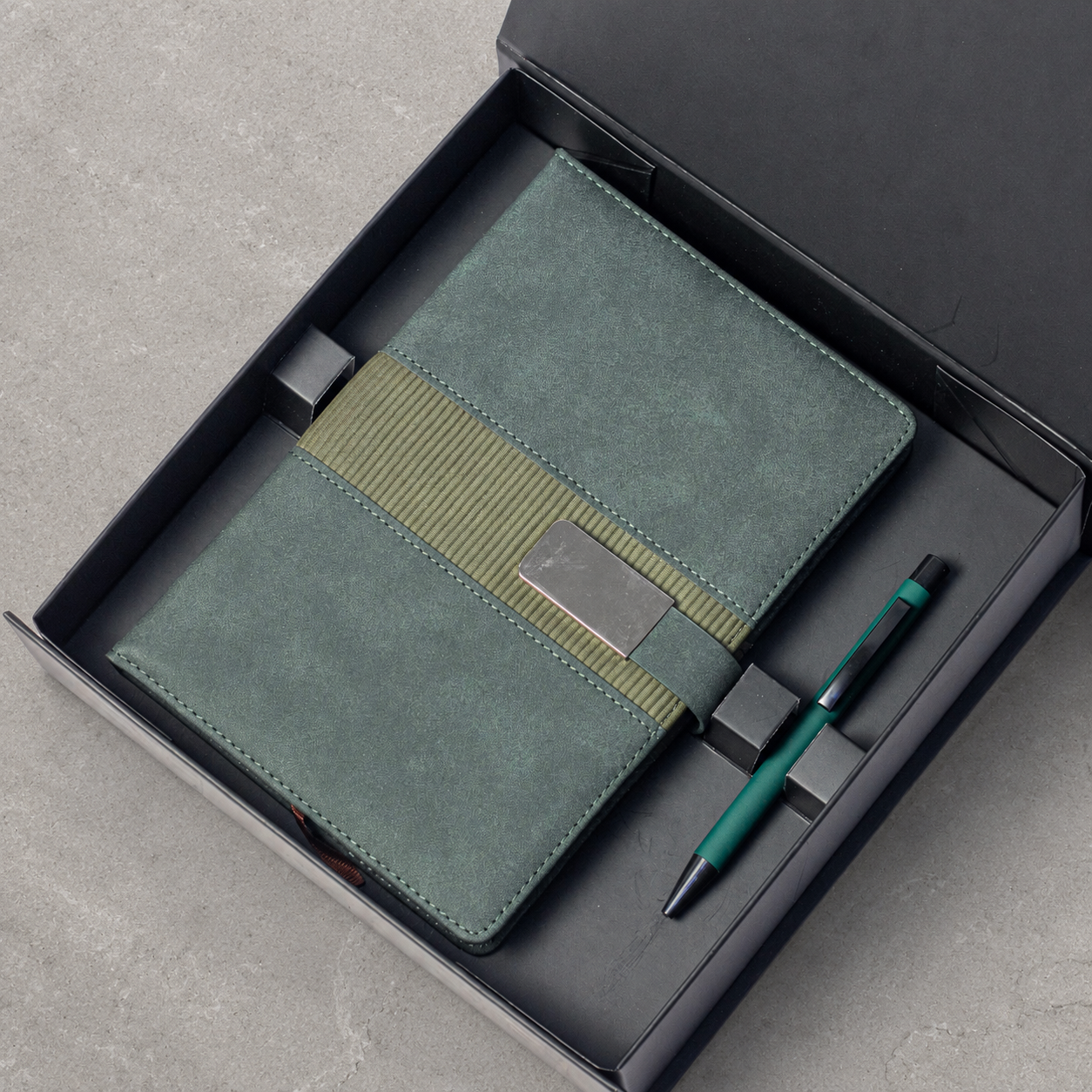 Notebook with buckle closure and matching pen arranged in a gift box
