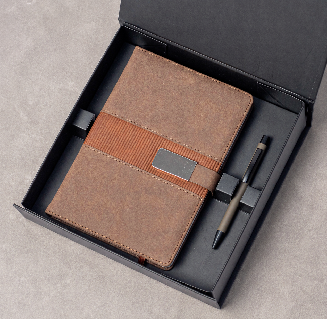 Notebook with buckle closure and matching pen arranged in a gift box