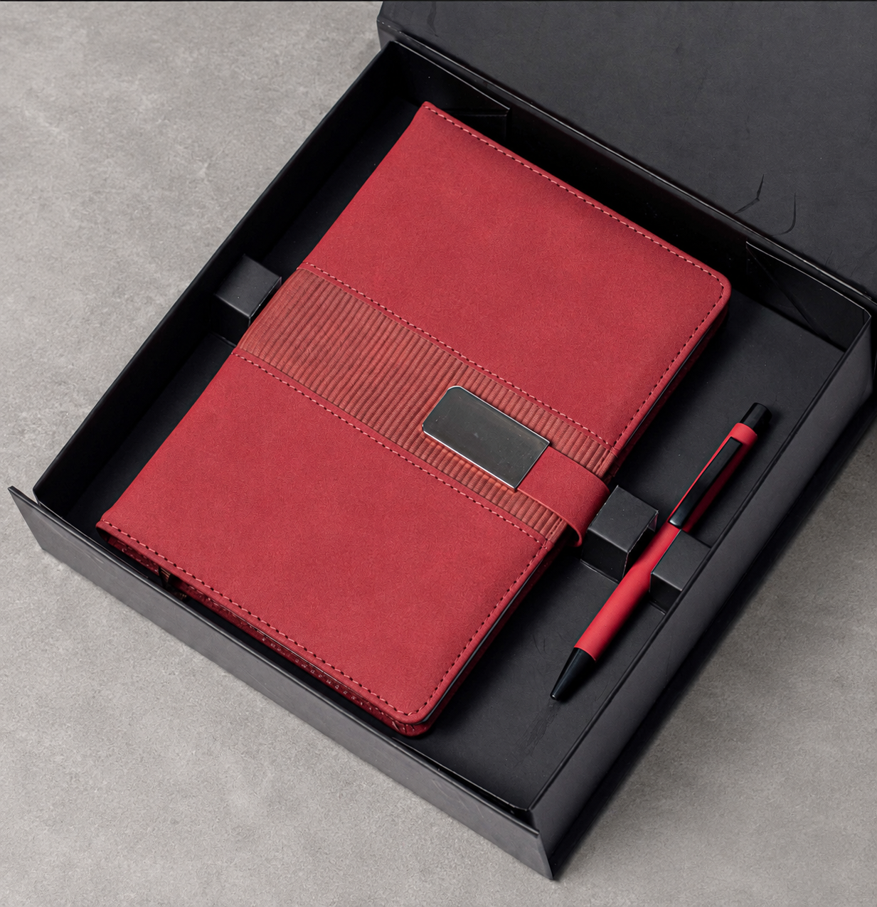 Notebook with buckle closure and matching pen arranged in a gift box