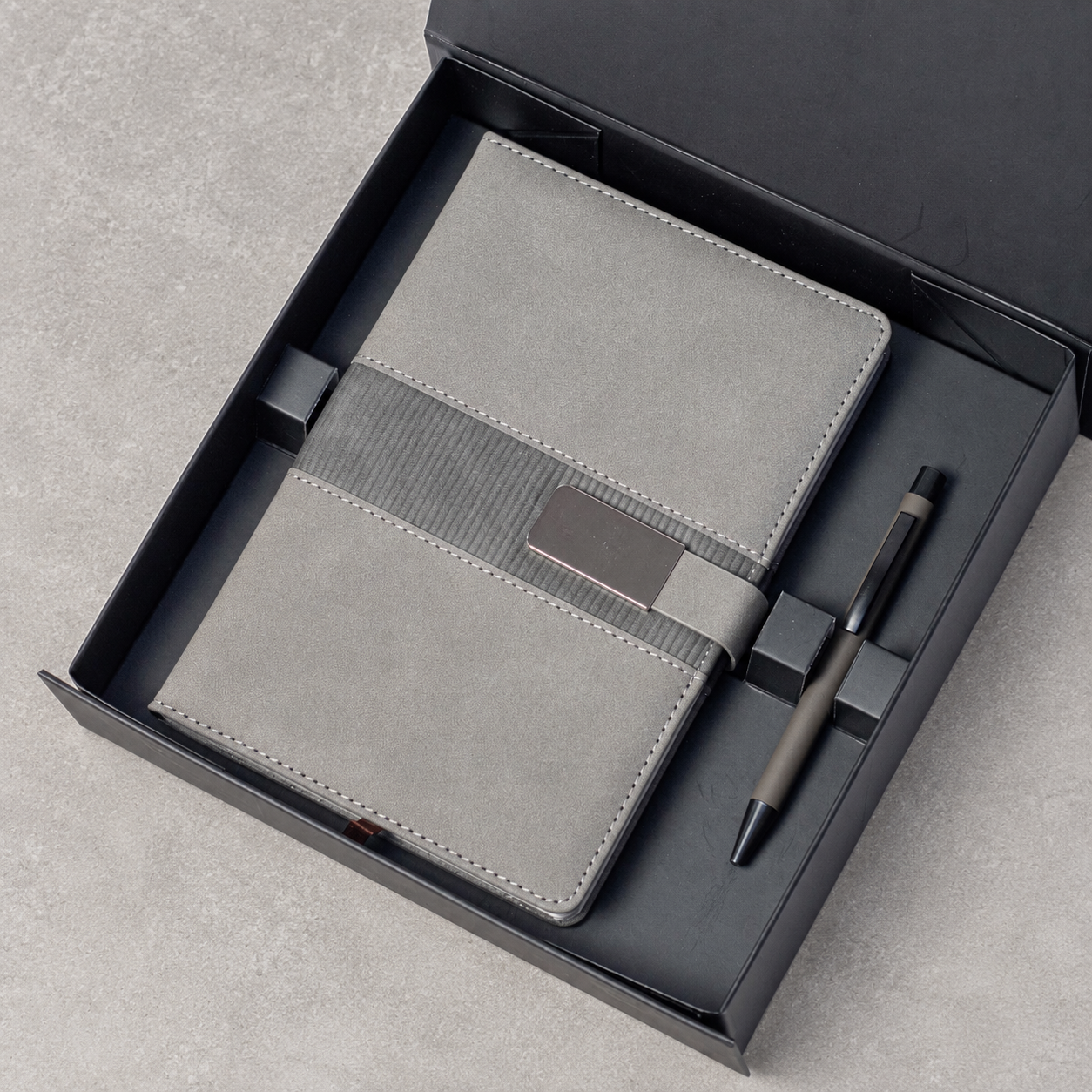 Notebook with buckle closure and matching pen arranged in a gift box