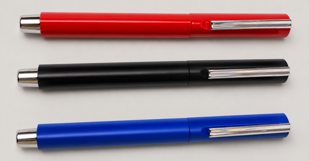Red, black and blue metallic pens with straight silver clips on a neutral studio background