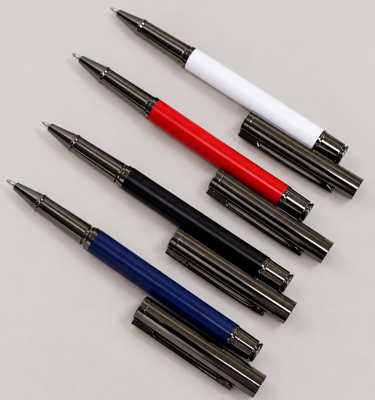 White, blue, red and black executive pens with dark gunmetal trim with writing tips exposed on a neutral studio background
